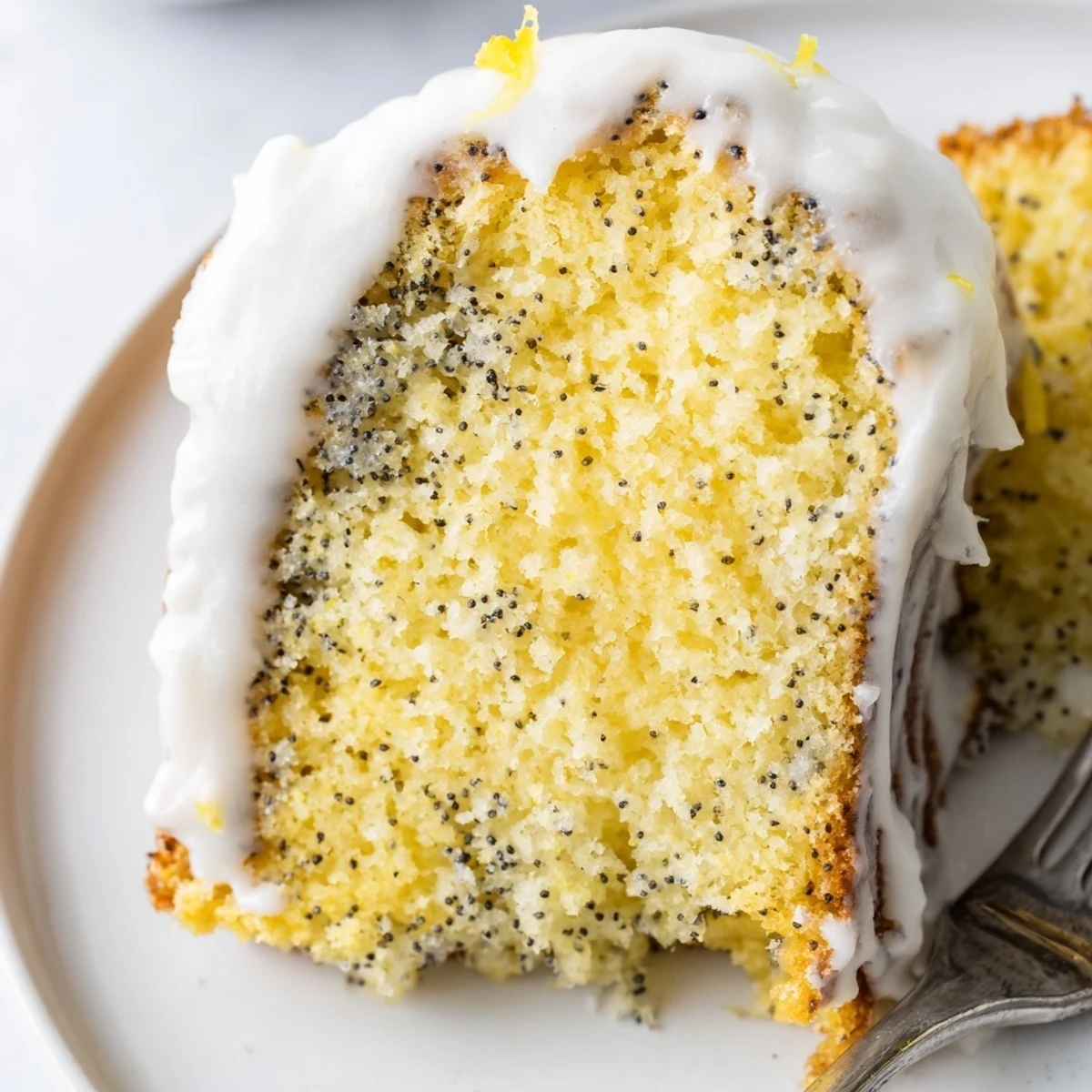 Bright Lemon Poppy Seed Cake with Icing on a marble board, ready to be served with hot tea.