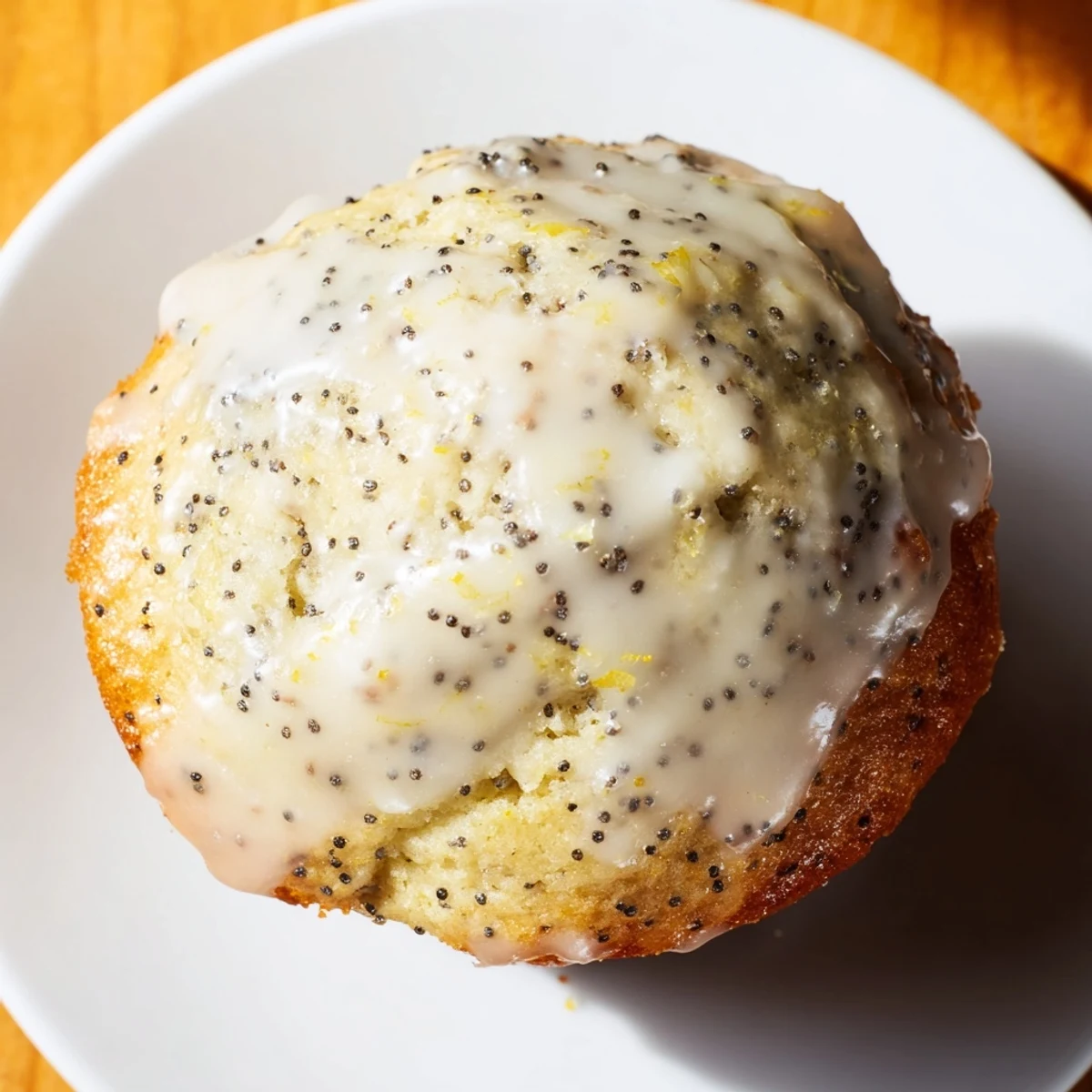 Freshly baked Lemon Poppy Seed Muffins with Lemon Glaze sit beside a steaming mug of Earl Grey tea on a cozy table.