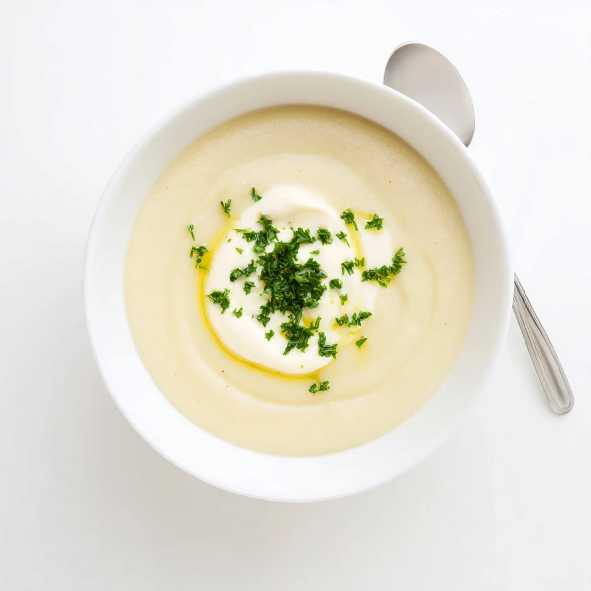 A bowl of velvety Roasted Parsnip and Garlic Soup, garnished with fresh chives and a swirl of cream, awaits on a rustic table.