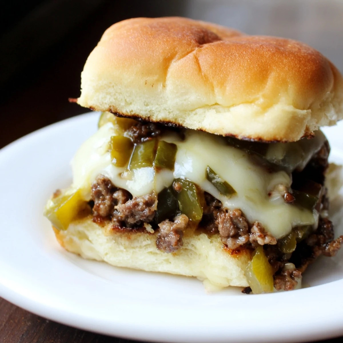 Golden-brown, cheesy Spicy Jalapeno Beef Sliders sit on a platter, with fresh jalapeño slices and crisp lettuce adding vibrant color.  
