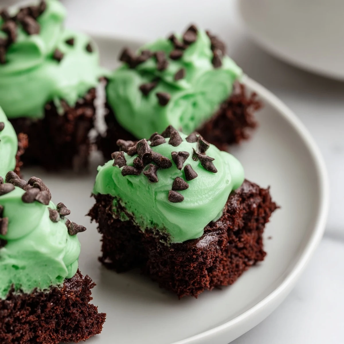 A close-up of St. Patrick's Day mint brownie bites showcasing their rich chocolate texture and glossy mint frosting.