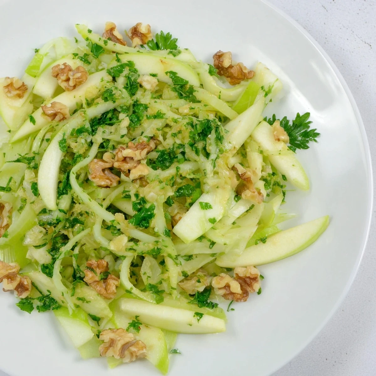 Green Apple and Celery Salad topped with chopped parsley and walnuts, served alongside grilled chicken for a light lunch.