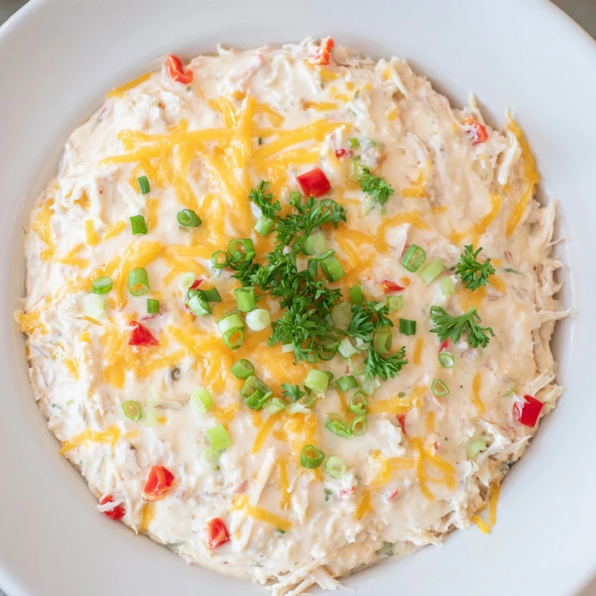 Golden-brown Mardi Gras Crab Dip bubbling in a baking dish with fresh parsley garnish.