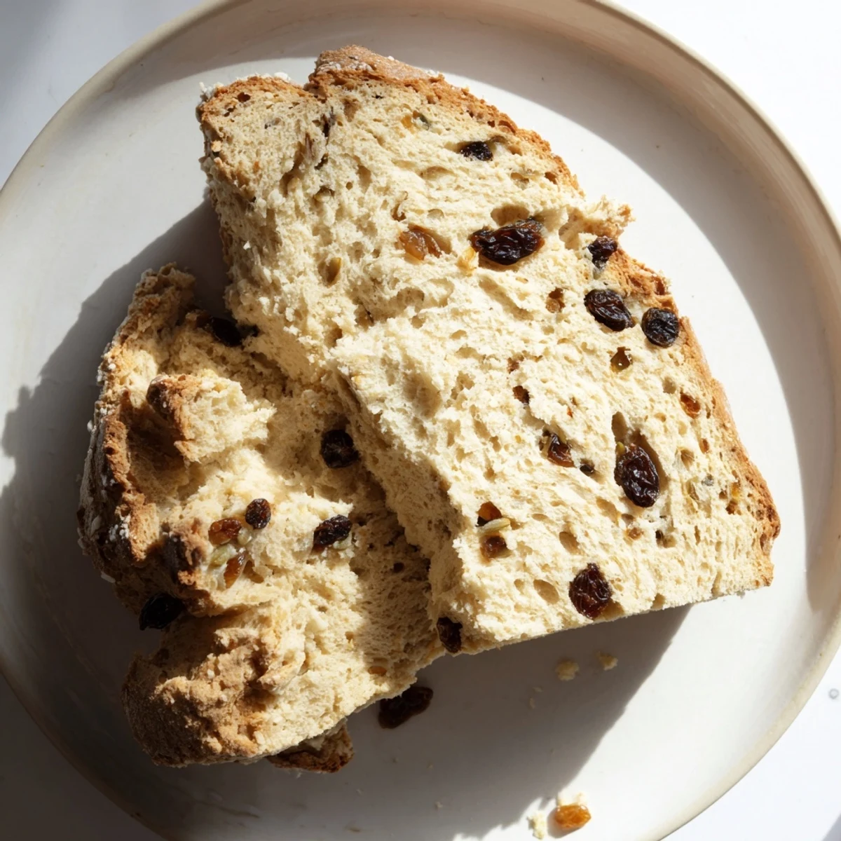 A rustic loaf of Irish Soda Bread with Raisins and Caraway, warm from the oven with a buttery brushed crust.
