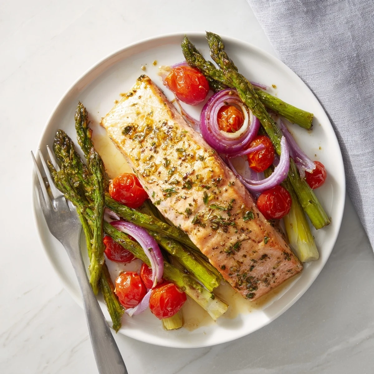 Lemon-garlic salmon, crisp asparagus, and juicy cherry tomatoes roasted on a single sheet pan for a quick dinner.