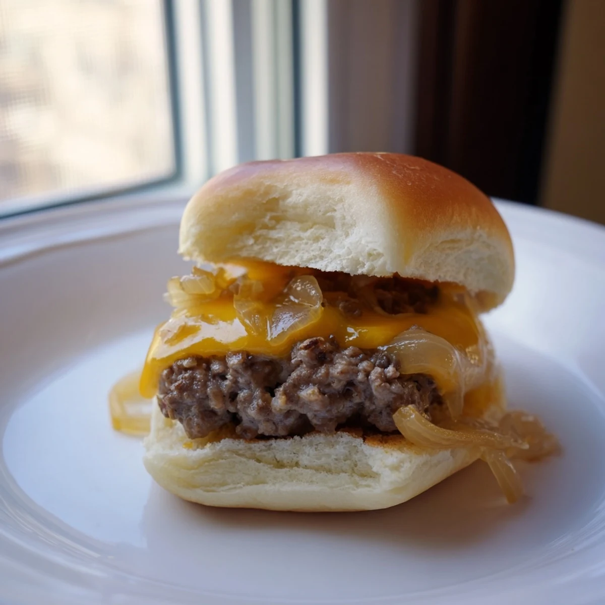 Juicy beef sliders with melted cheddar cheese and sweet caramelized onions on soft toasted buns.
