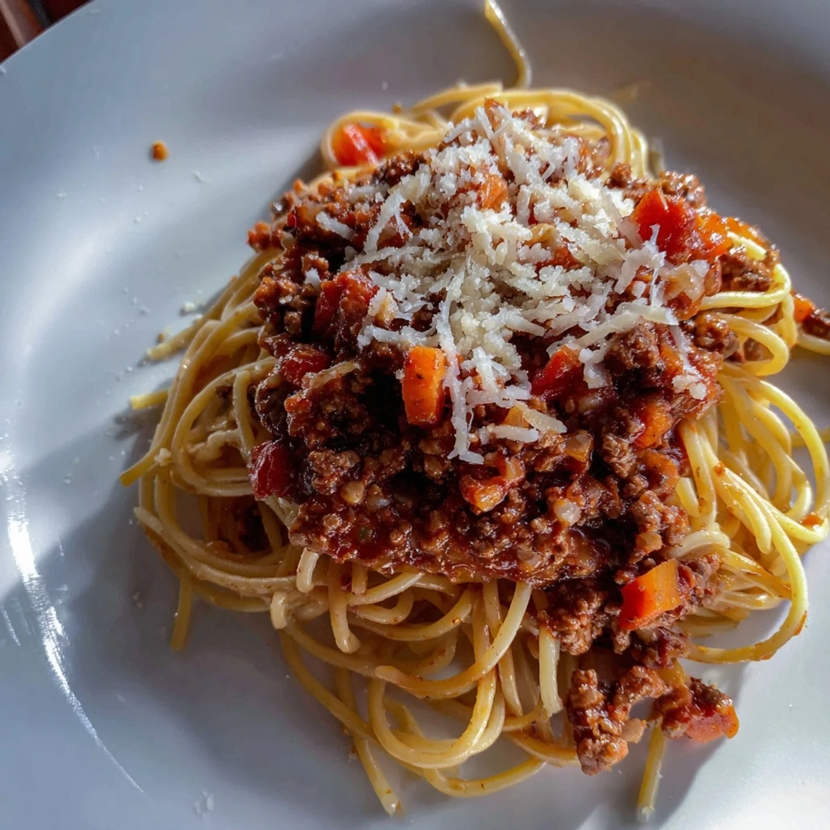 A close-up of hearty Beef Bolognese with Spaghetti and Parmesan, rich red sauce clinging to al dente noodles topped with fresh grated cheese.