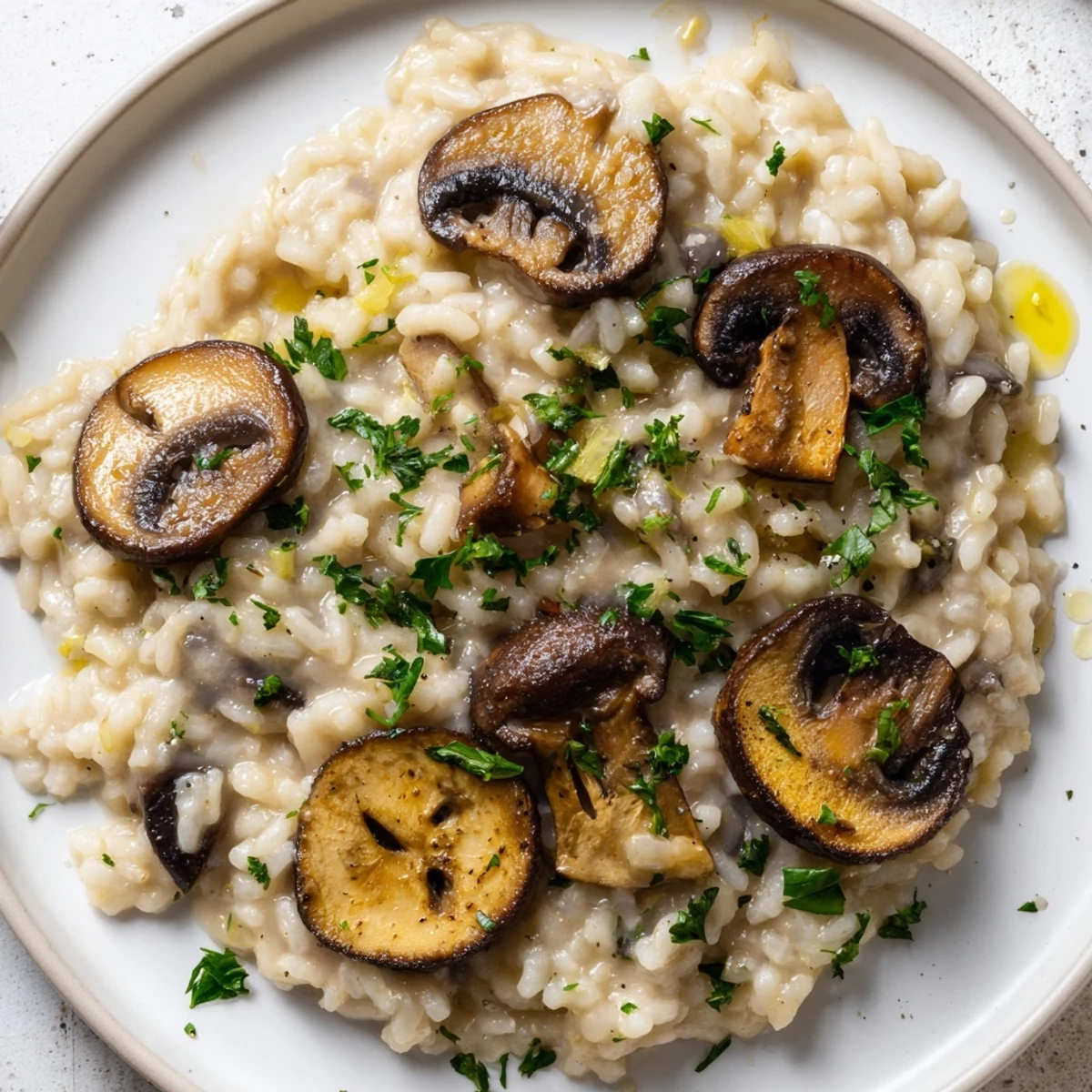 Earthy mushrooms and truffle oil top this creamy risotto served in a white ceramic dish.