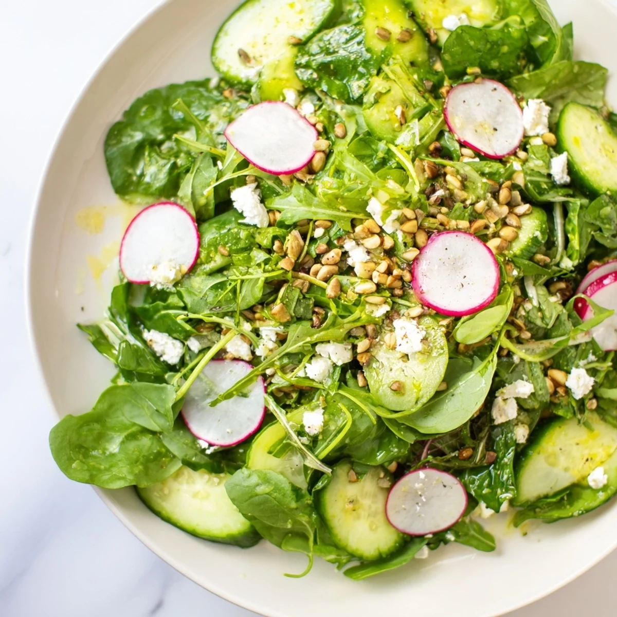 Crisp Spring Greens Salad with Lemon Vinaigrette served fresh with cucumber slices and toasted almonds on the side.