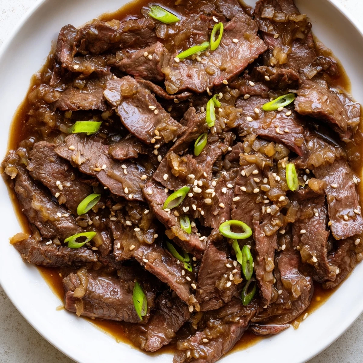 Steamed white rice topped with tender Ultimate Slow Cooker Mongolian Beef glistening in a rich, savory-sweet sauce and garnished with green onions.