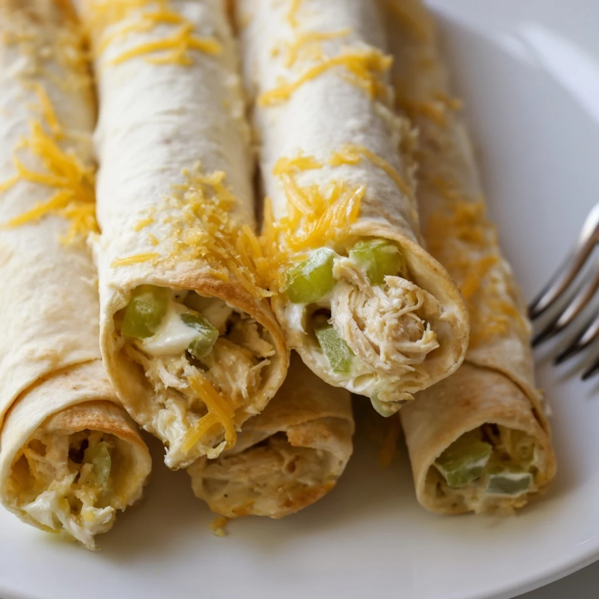 Freshly baked Dill Pickle Ranch Chicken Taquitos in a serving basket, showing golden, crispy shells and a drizzle of extra ranch on top.