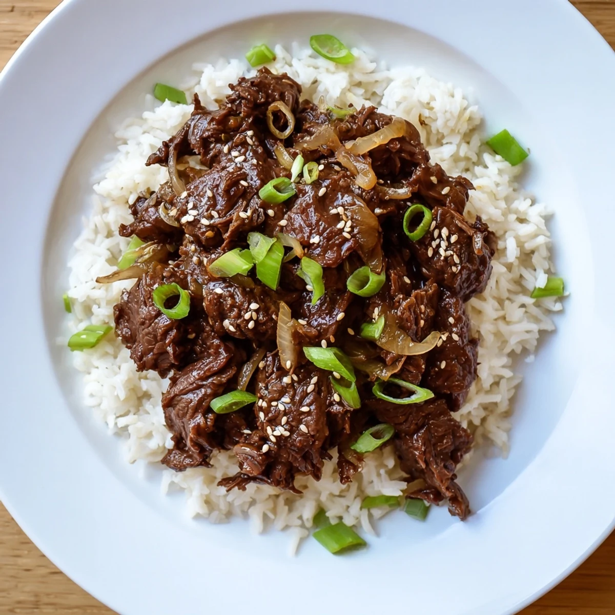 Tender Crock Pot Korean Beef ready for serving, spooned over fluffy jasmine rice with a sprinkle of fresh sesame seeds.