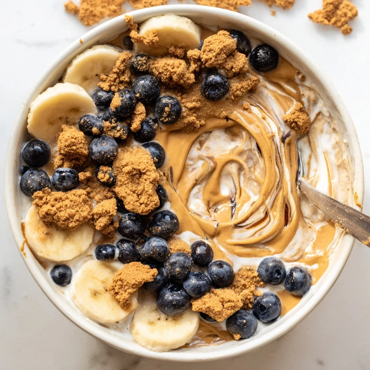 Creamy Quick Biscoff Overnight Oats layered in a jar, topped with crushed cookies and a banana slice for a cozy breakfast.