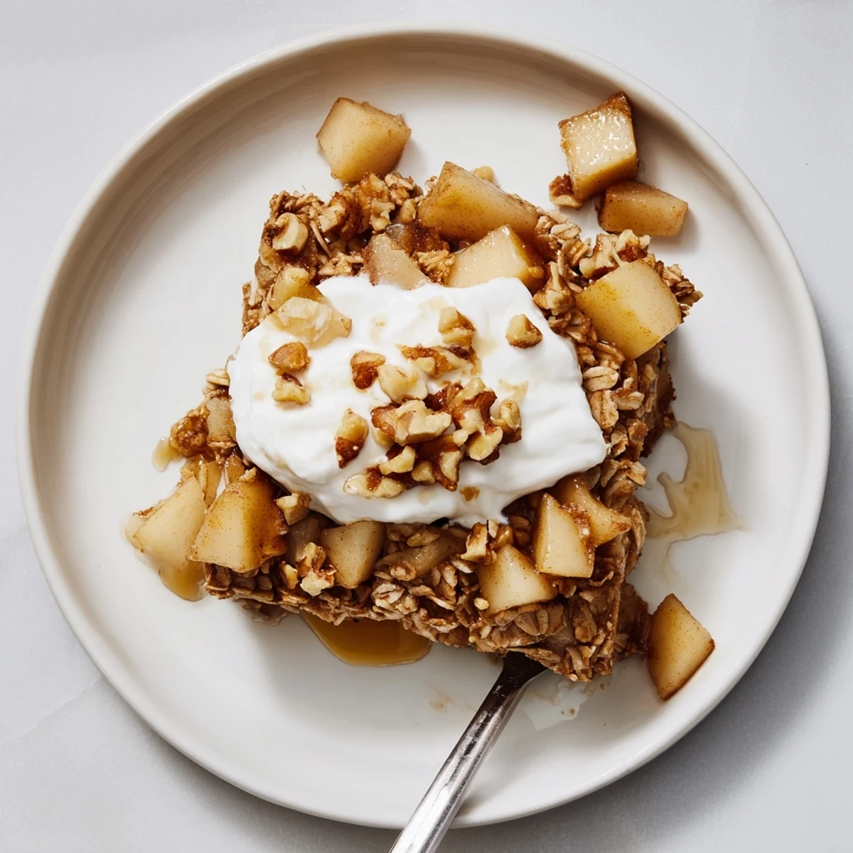 Warm squares of Baked Apple Oatmeal With Greek Yogurt, featuring tender oats and cinnamon-spiced apples, ready for breakfast.