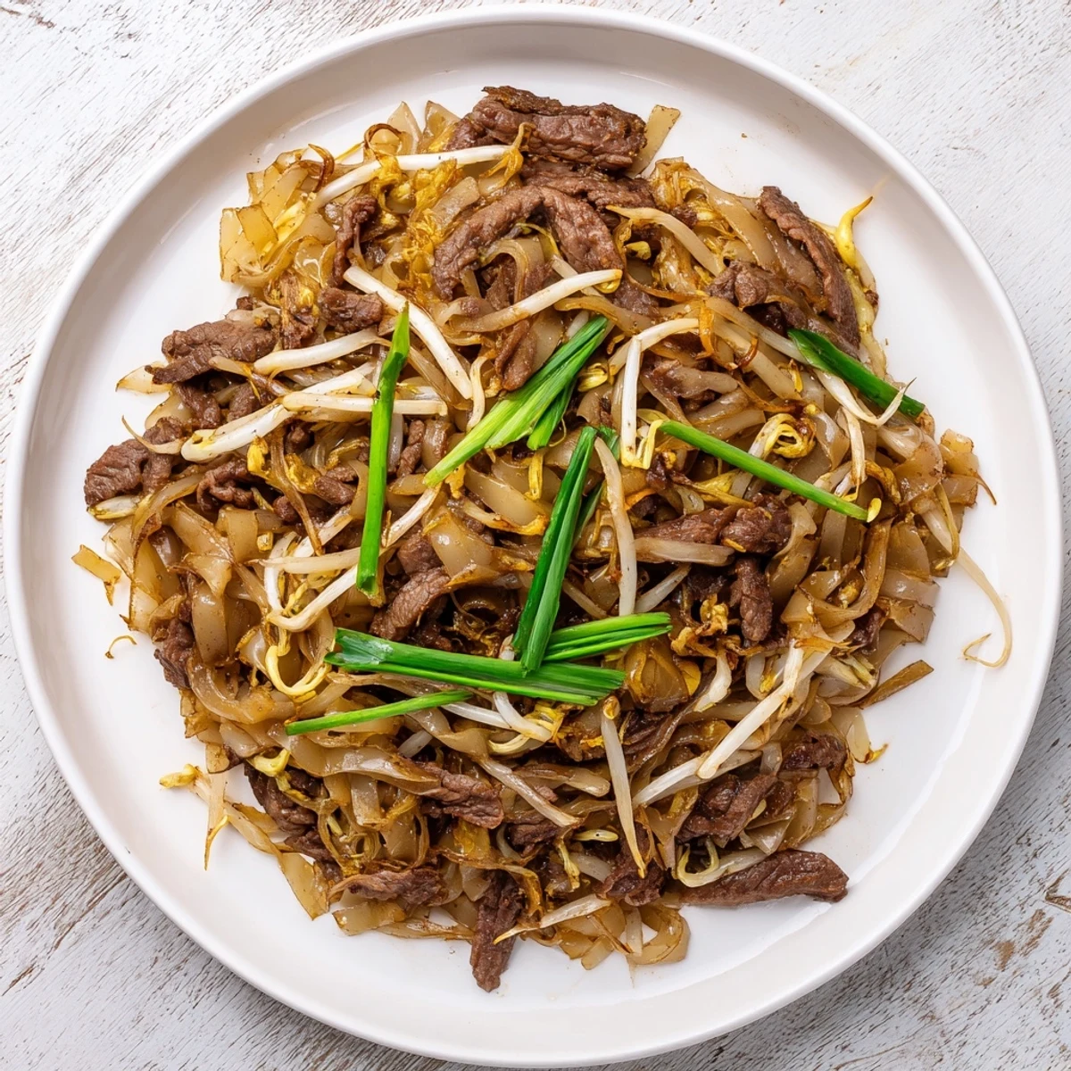 Steaming bowl of classic Beef Chow Fun, featuring wide rice noodles, tender beef strips, and crisp bean sprouts.