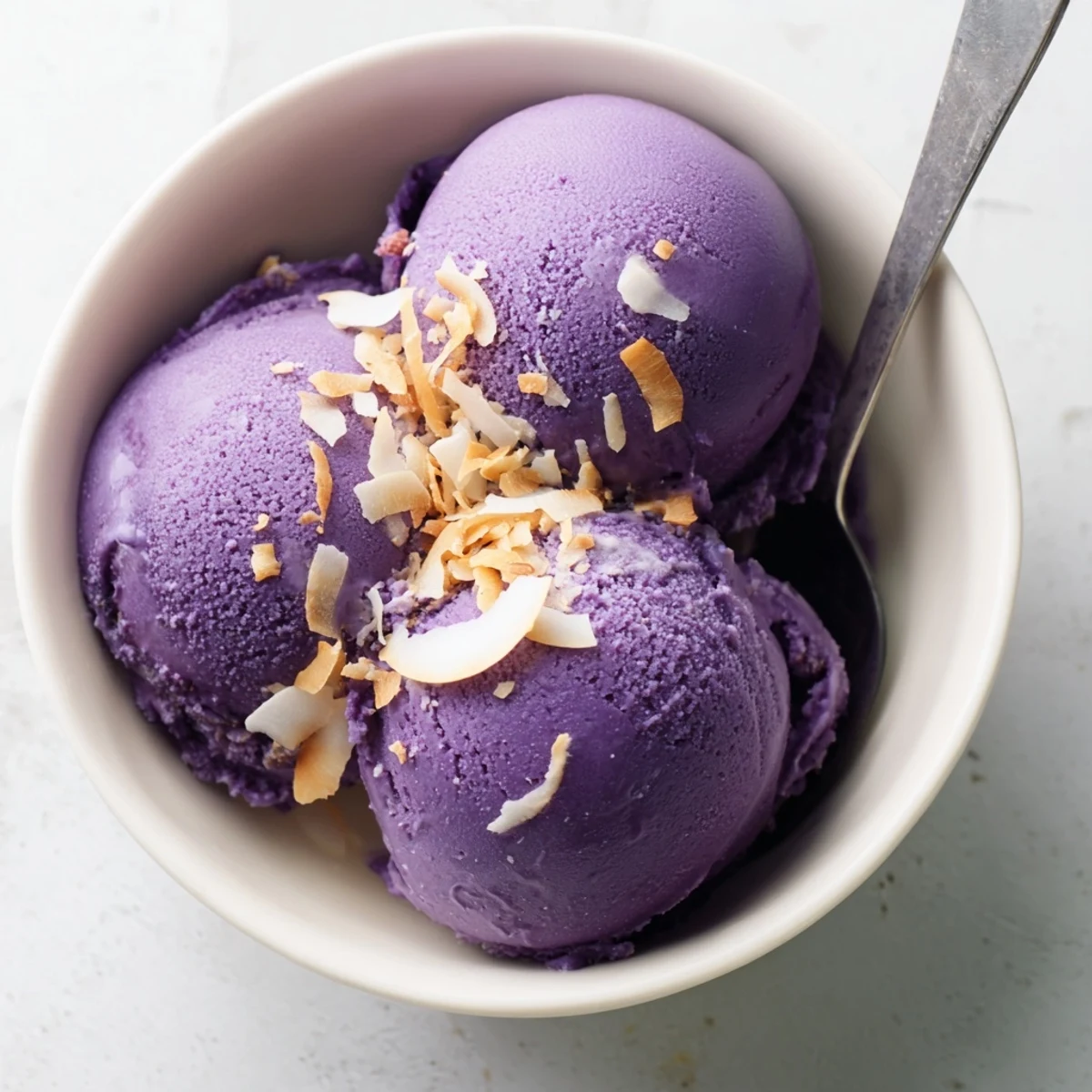Close-up of creamy Ube Ice Cream melting slightly in a glass dish, showcasing its rich color and smooth, velvety texture.