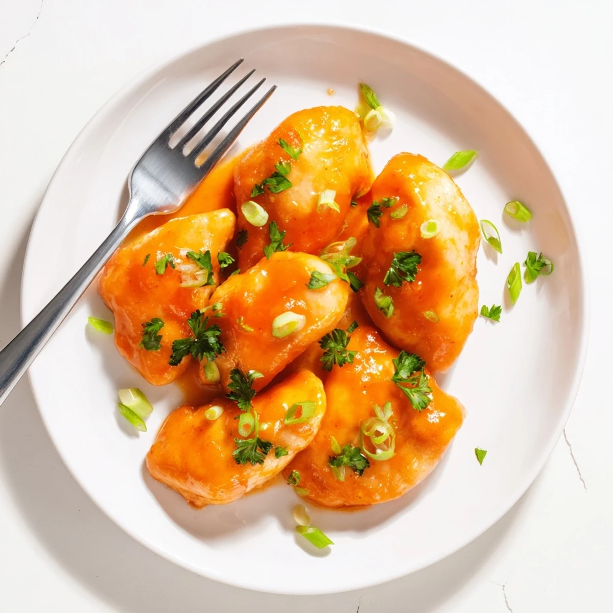 A close-up of baked Classic Apricot Chicken, glistening with sweet sauce and herbs on a plate.