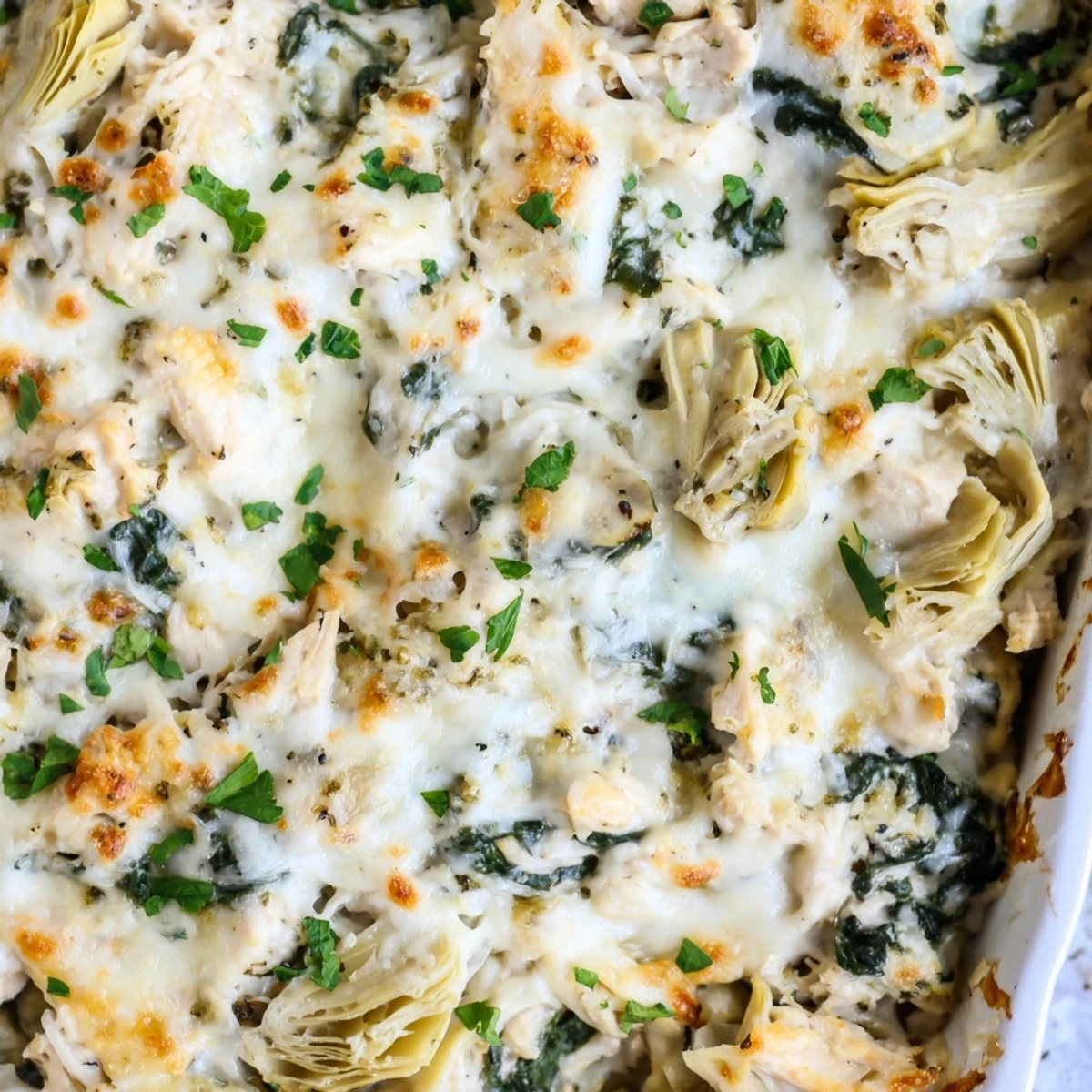 Hearty chicken spinach and artichoke casserole sprinkled with fresh parsley and parmesan cheese