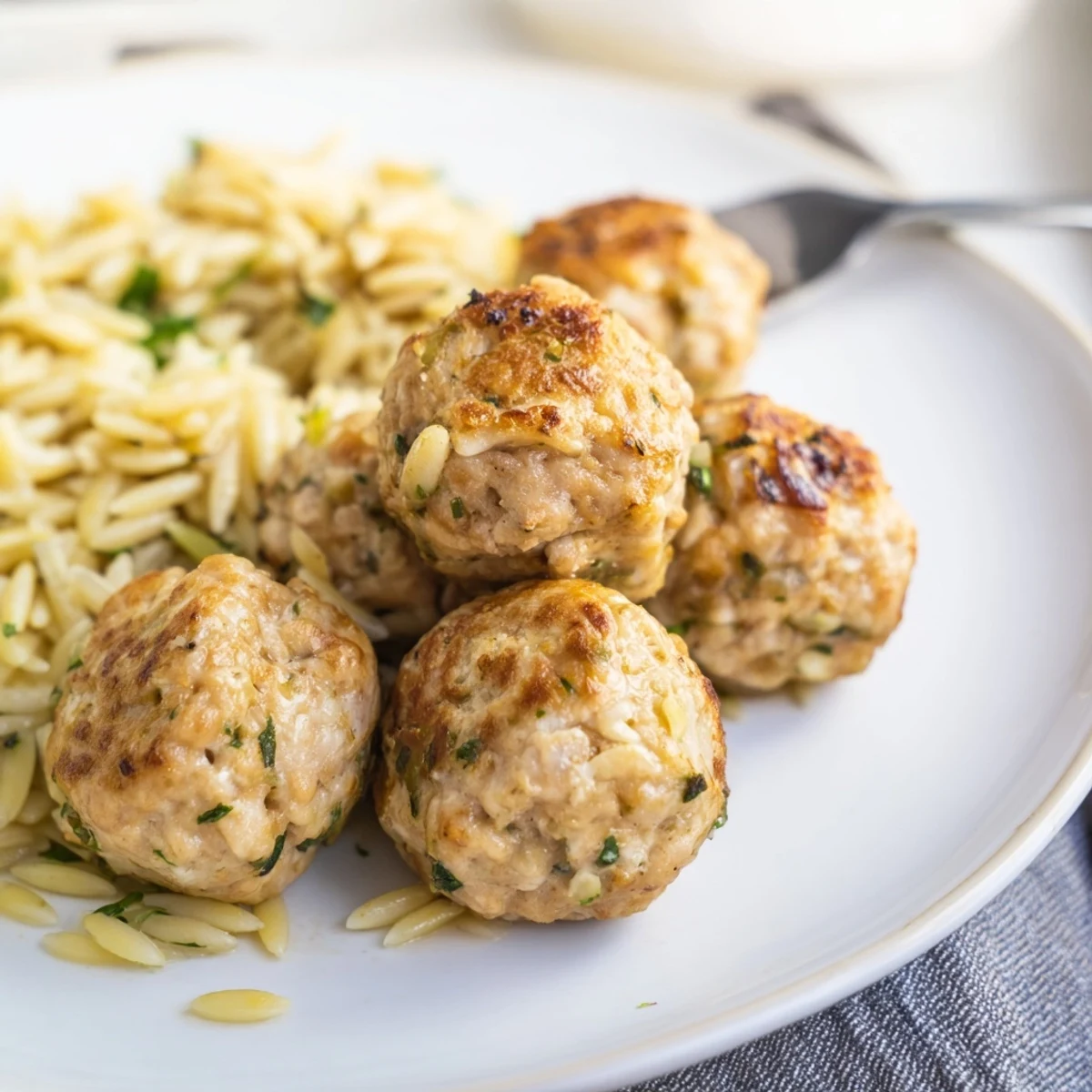 Juicy Greek chicken meatballs with lemon orzo topped with dill parsley and optional feta cheese