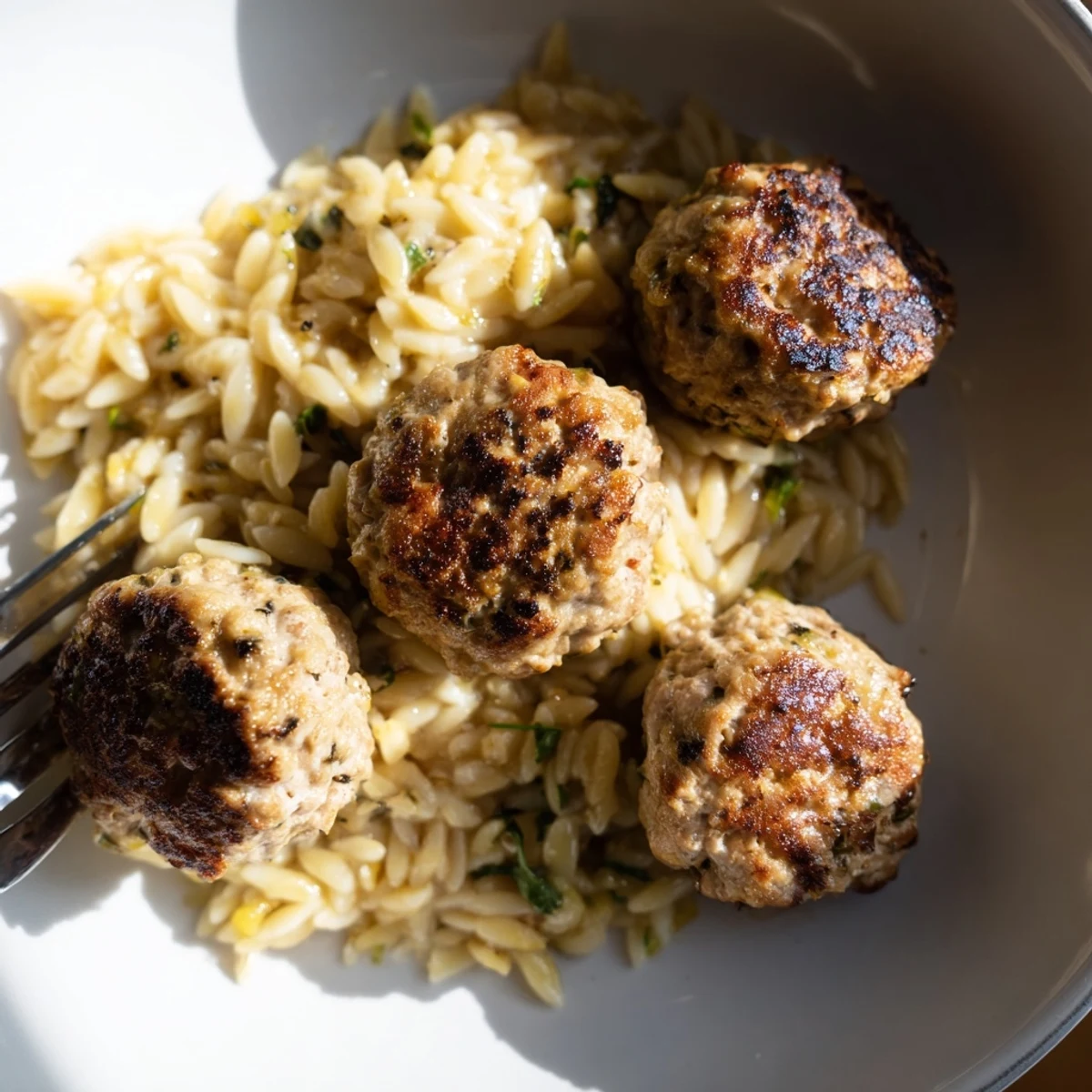 Mediterranean style ground chicken meatballs served atop tender lemon garlic orzo with fresh green herbs