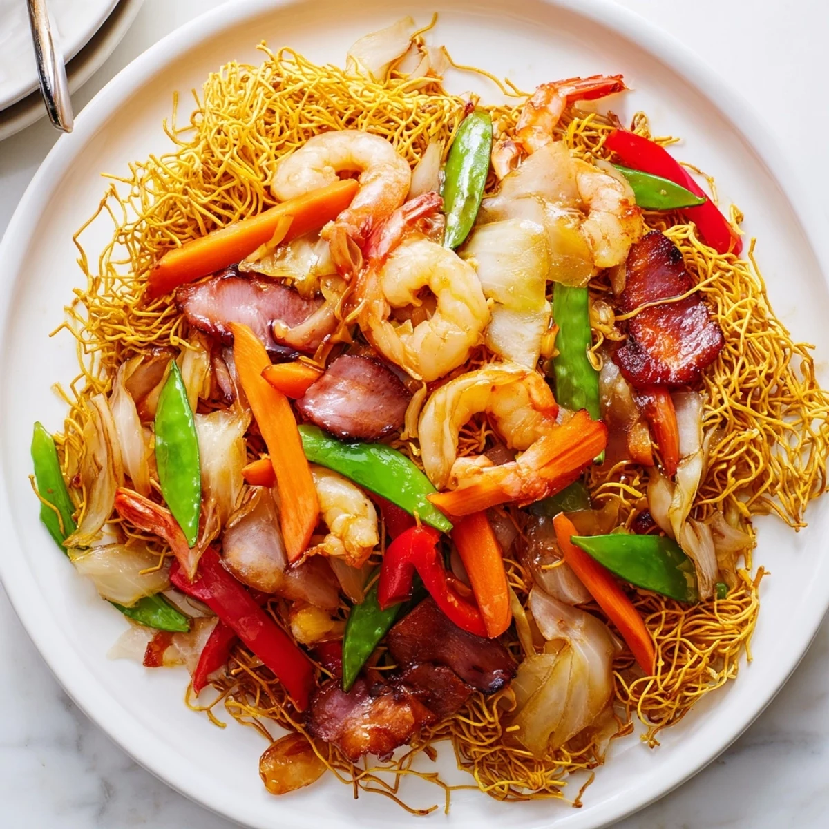 Golden Cantonese chow mein topped with colorful stir-fried vegetables and savory meats