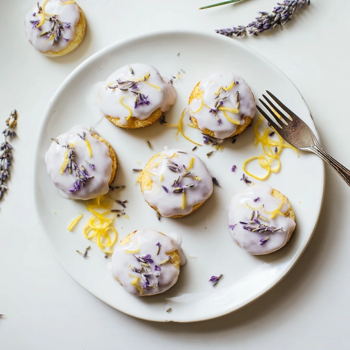 Small bundt-shaped lemon cakes topped with purple lavender glaze and fresh zest