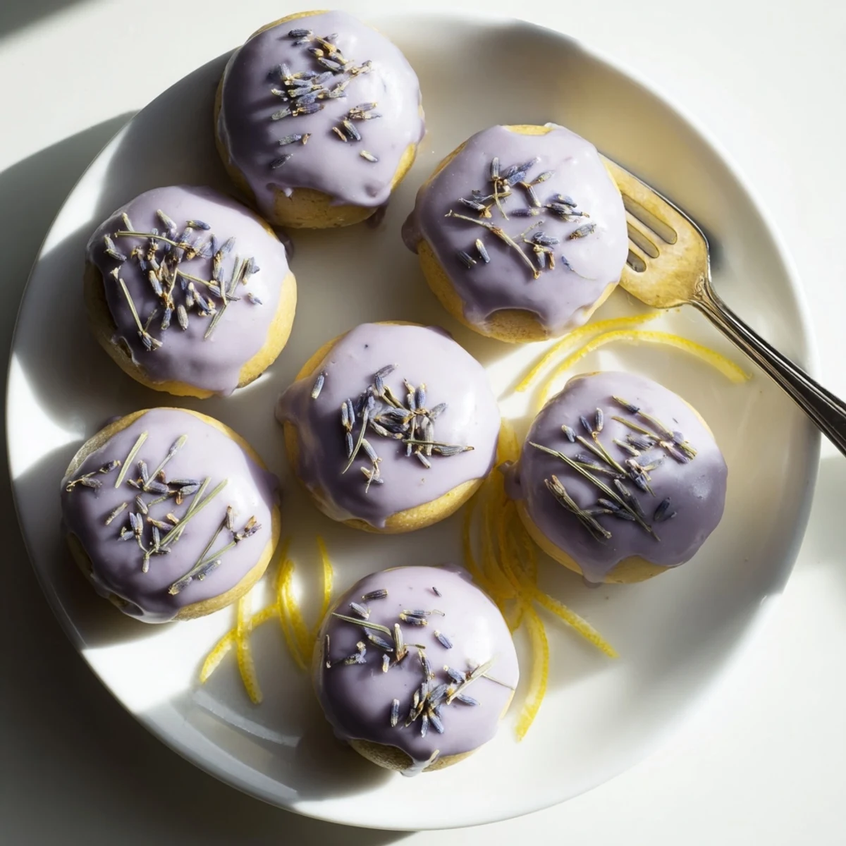 Moist lemon mini cakes decorated with floral lavender glaze on serving platter