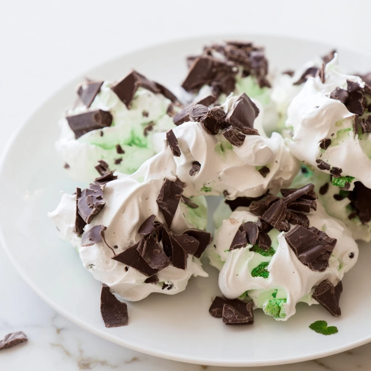 Close-up of dark chocolate and mint chip cloud cookies showing crisp texture and melting chocolate chunks.