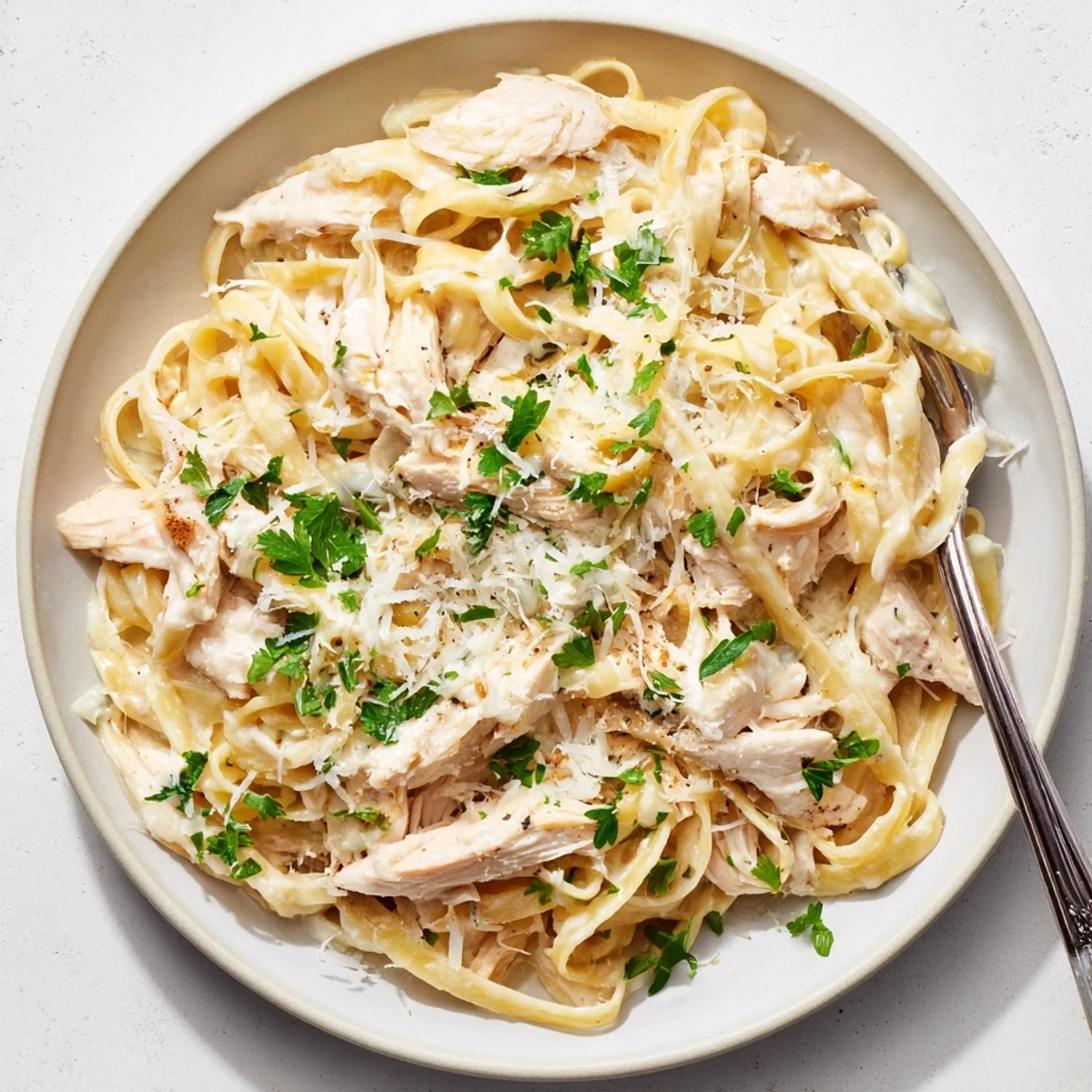 Homemade Chicken Alfredo in a crock pot, showcasing shredded chicken over al dente fettuccine.