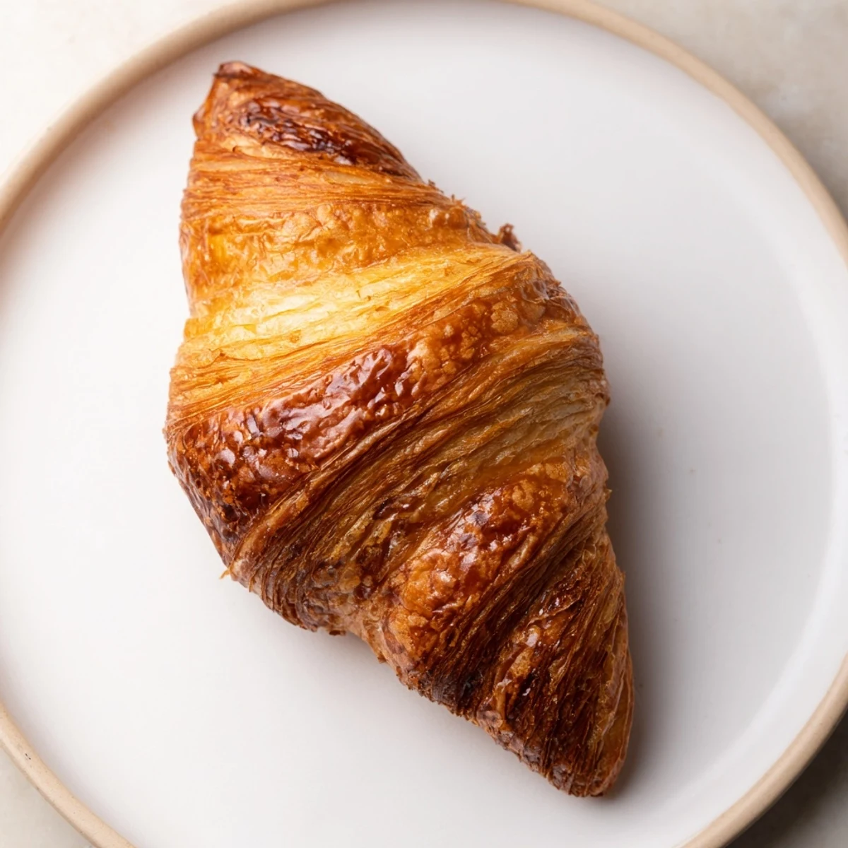 Freshly baked air fryer homemade croissants arranged on a wooden board with glossy egg wash finish