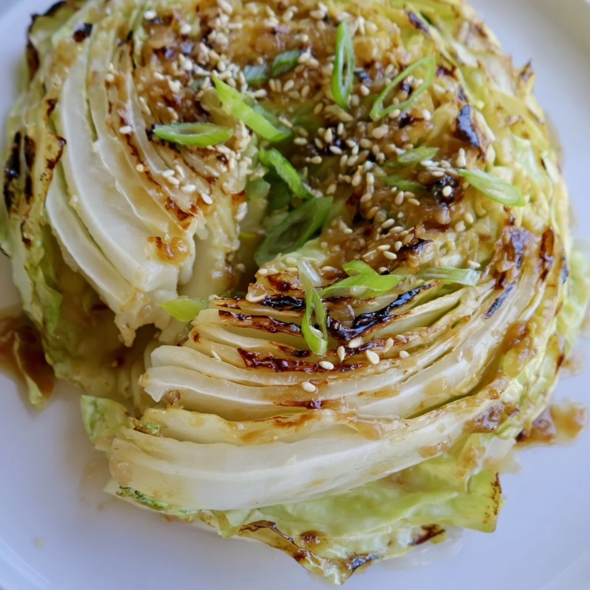 Golden roasted miso butter cabbage wedges drizzled with savory umami sauce and sesame seeds
