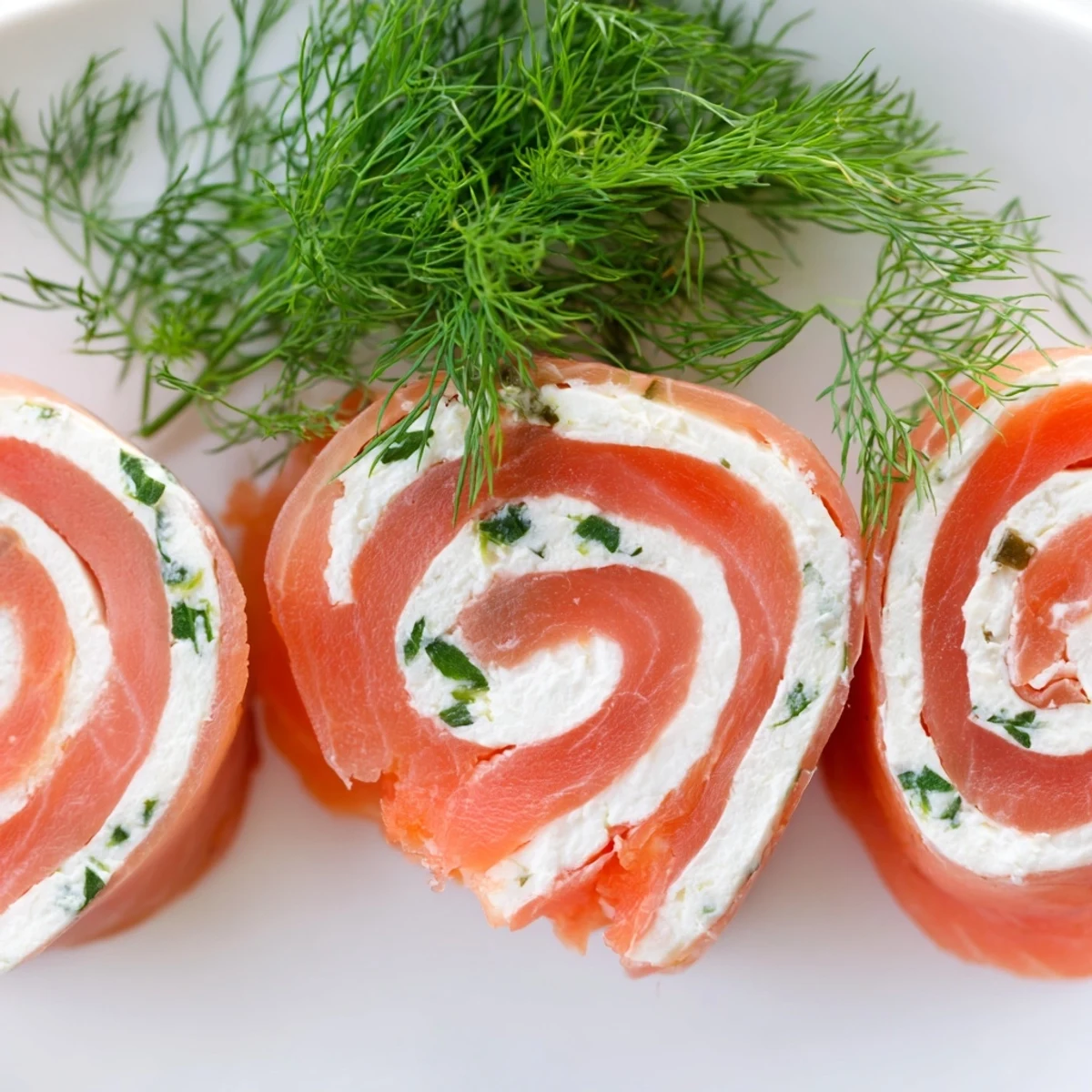 Spiral smoked salmon roll ups with cream cheese filling plated on white serving dish
