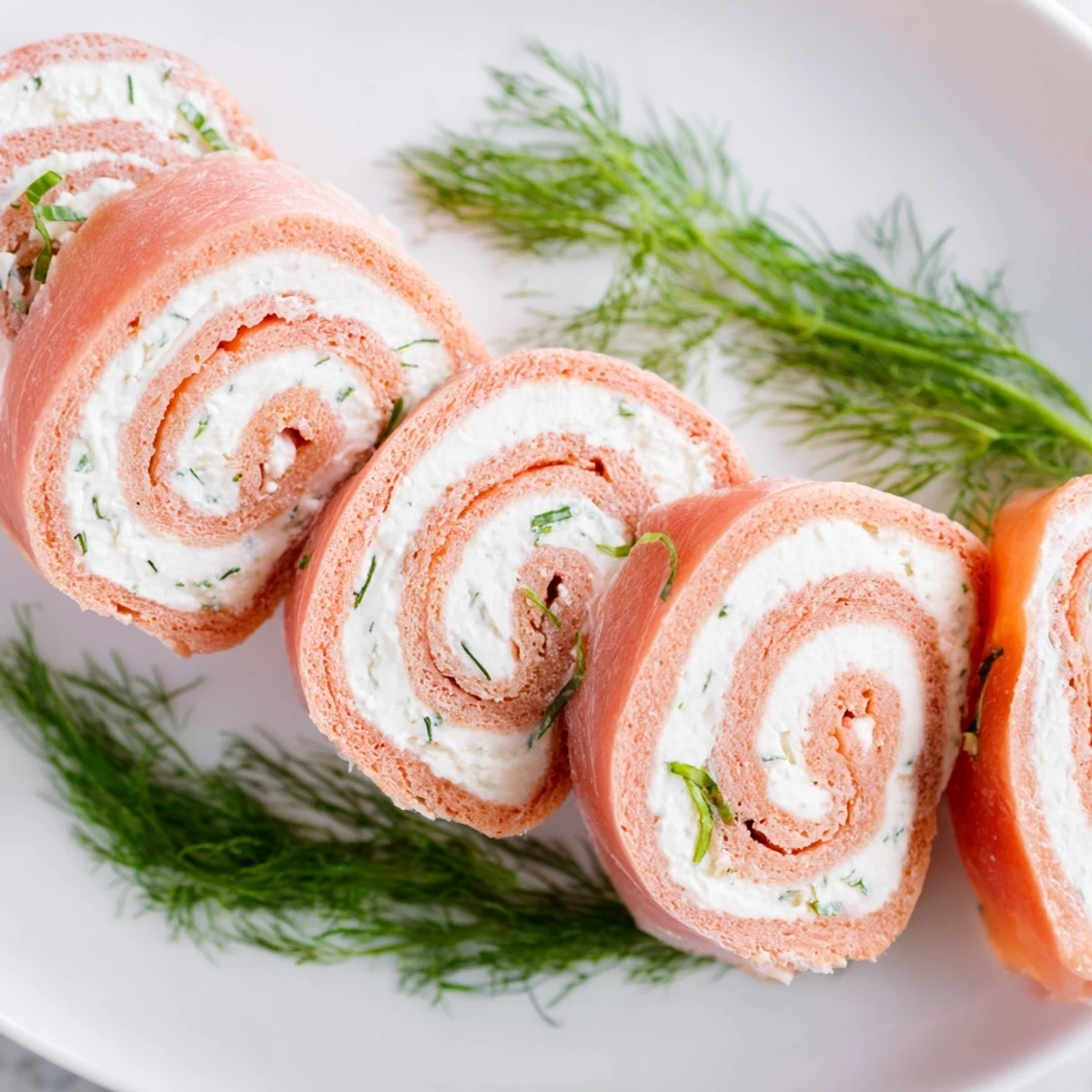 Close-up view of sliced smoked salmon roll ups revealing creamy herb center layers