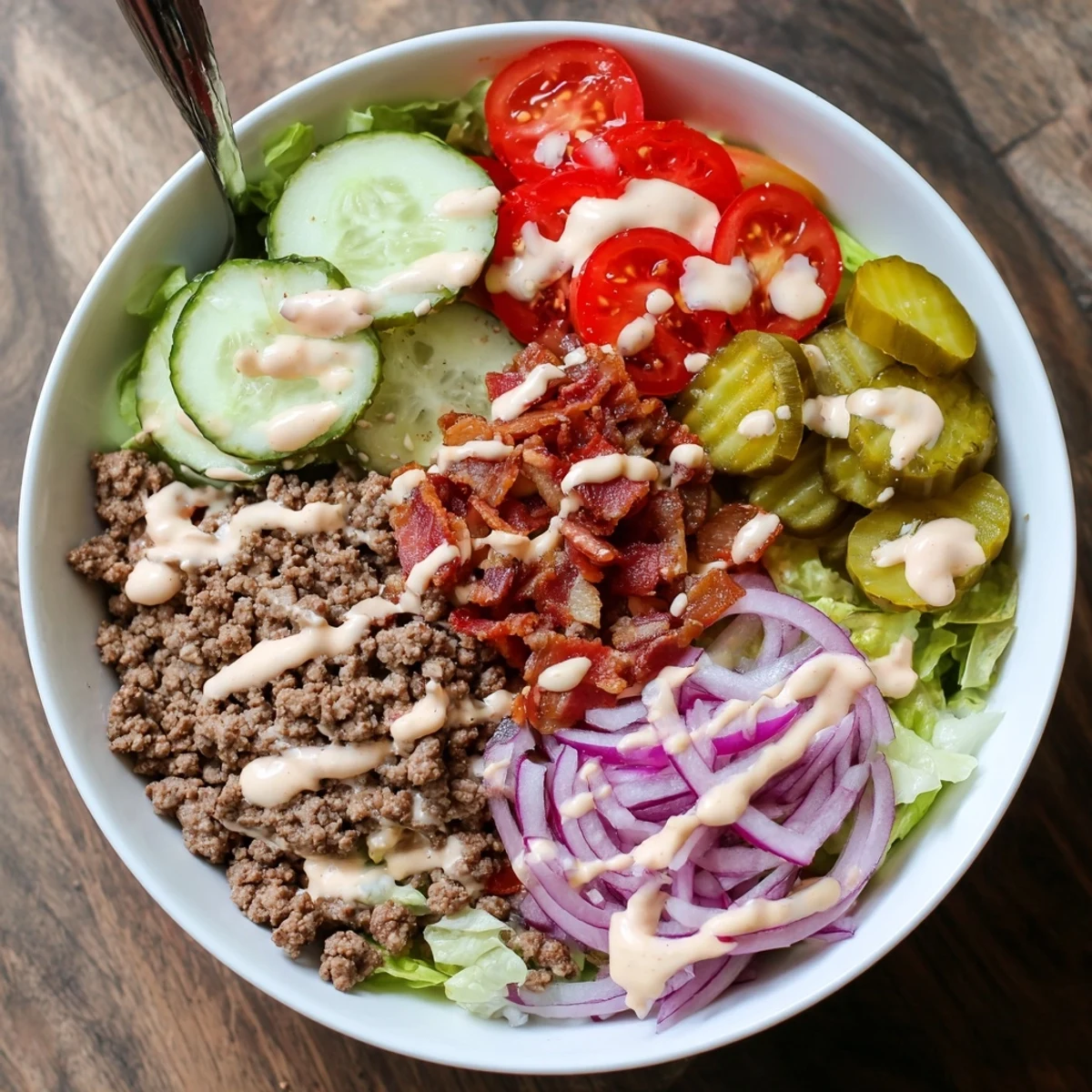 Hearty American-style burger bowl piled high with cooked ground beef, cherry tomatoes, red onions, and special sauce topping