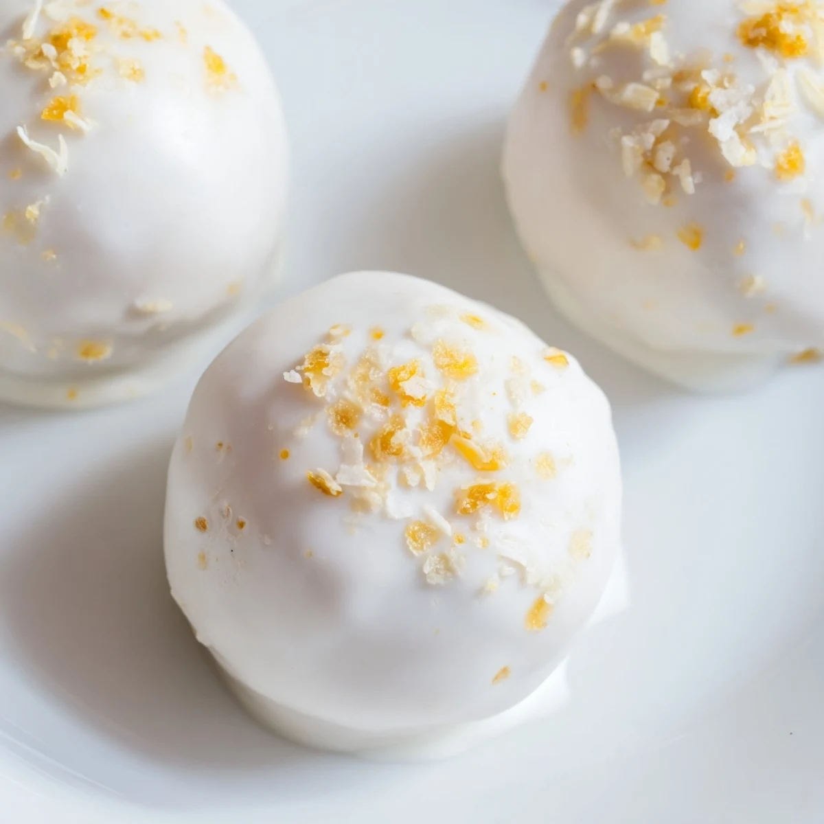 Creamy white chocolate mango truffles dusted with coconut on a marble serving board
