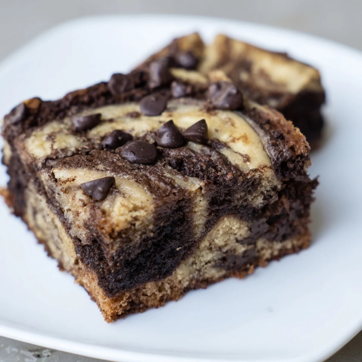 Freshly baked banana bread brownie bars swirled with chocolate and served on a white plate