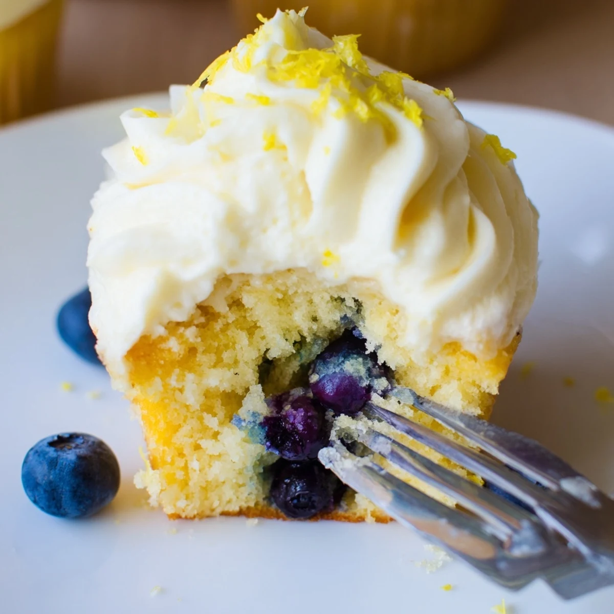 Zesty lemon blueberry cupcakes with smooth cream cheese frosting and blueberry garnish on serving tray