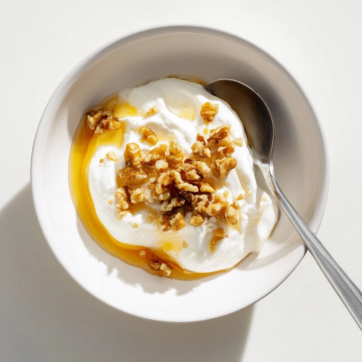 Thick Greek yogurt spooned into a glass jar with drizzled honey and berries