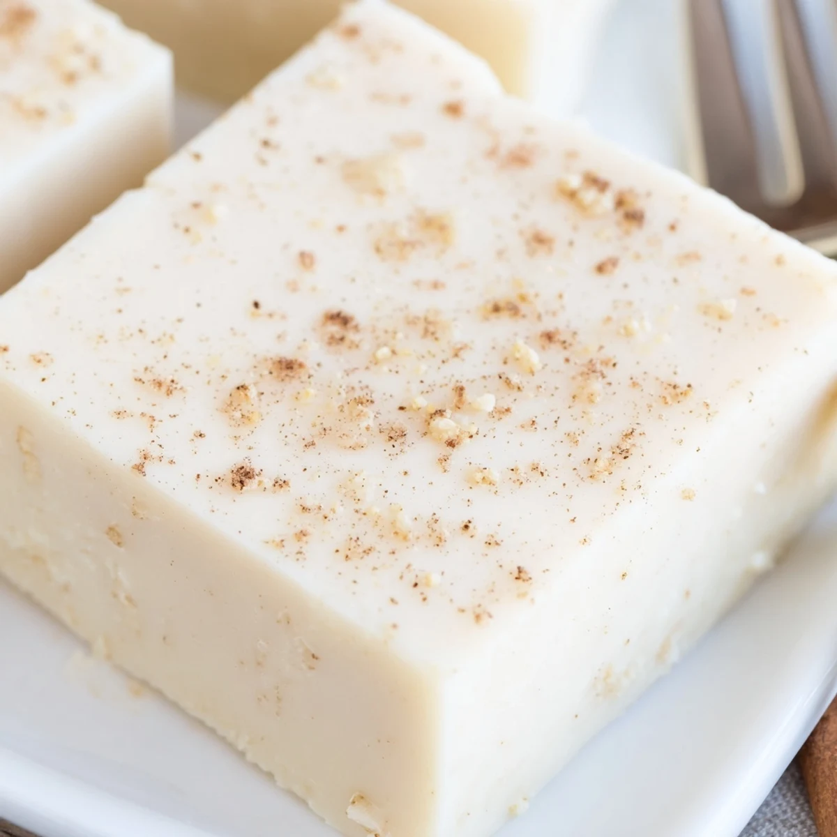 Slices of Eggnog Fudge cooling on parchment, rich vanilla and spice aroma