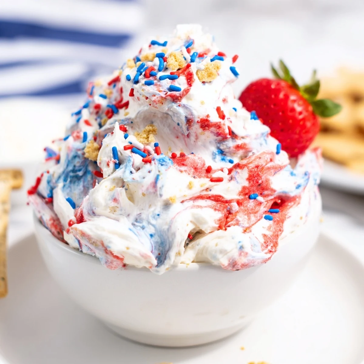 Red White And Blue Funfetti Dip topped with reserved sprinkles, served with strawberries