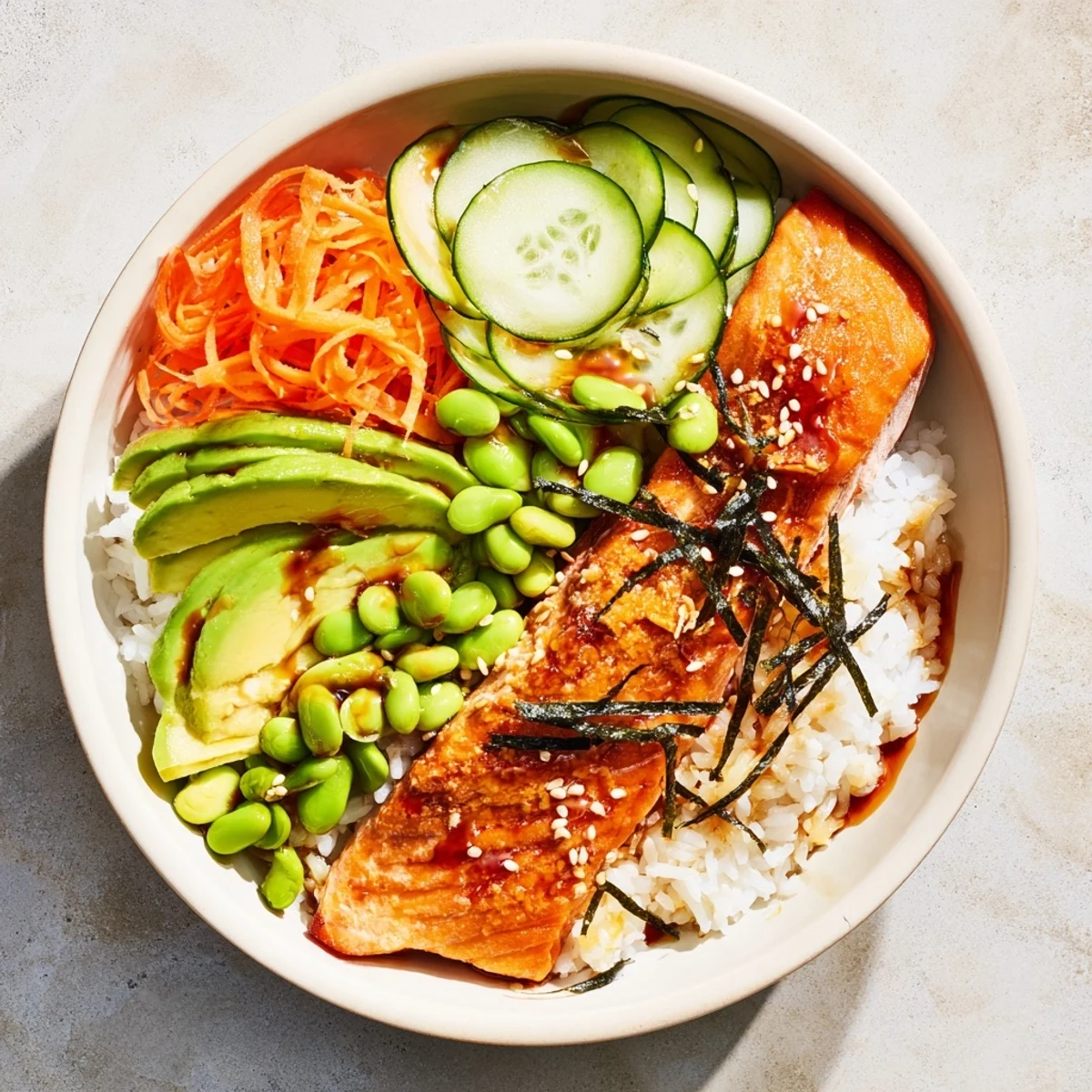 Sizzling crispy salmon arranged over steaming white rice with edamame carrots scallions and tangy honey sriracha dressing