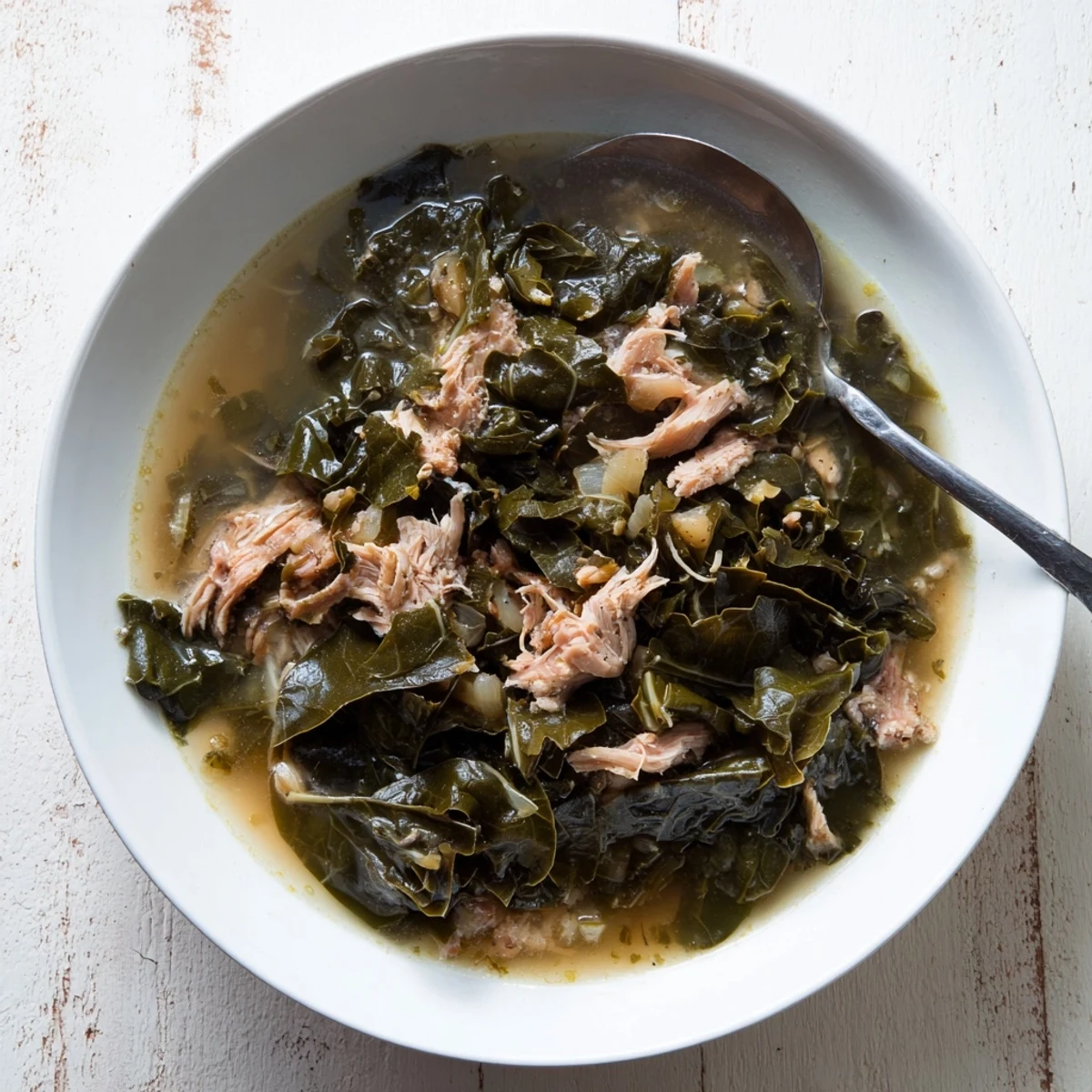 Vibrant green collard greens slow-cooked with aromatic onions and savory seasonings in a large Dutch oven