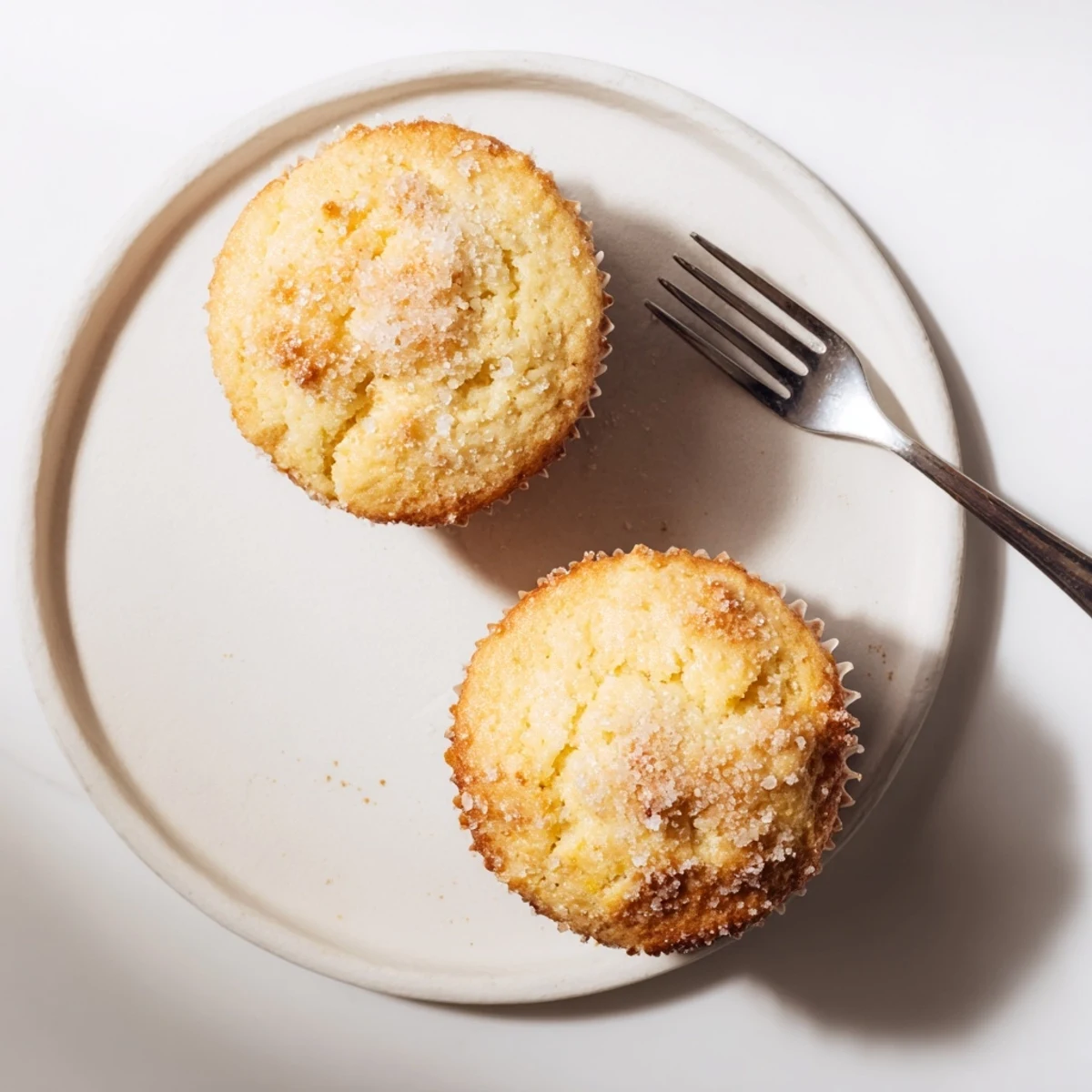 Golden lemon cream cheese muffins topped with coarse sugar on a wire rack