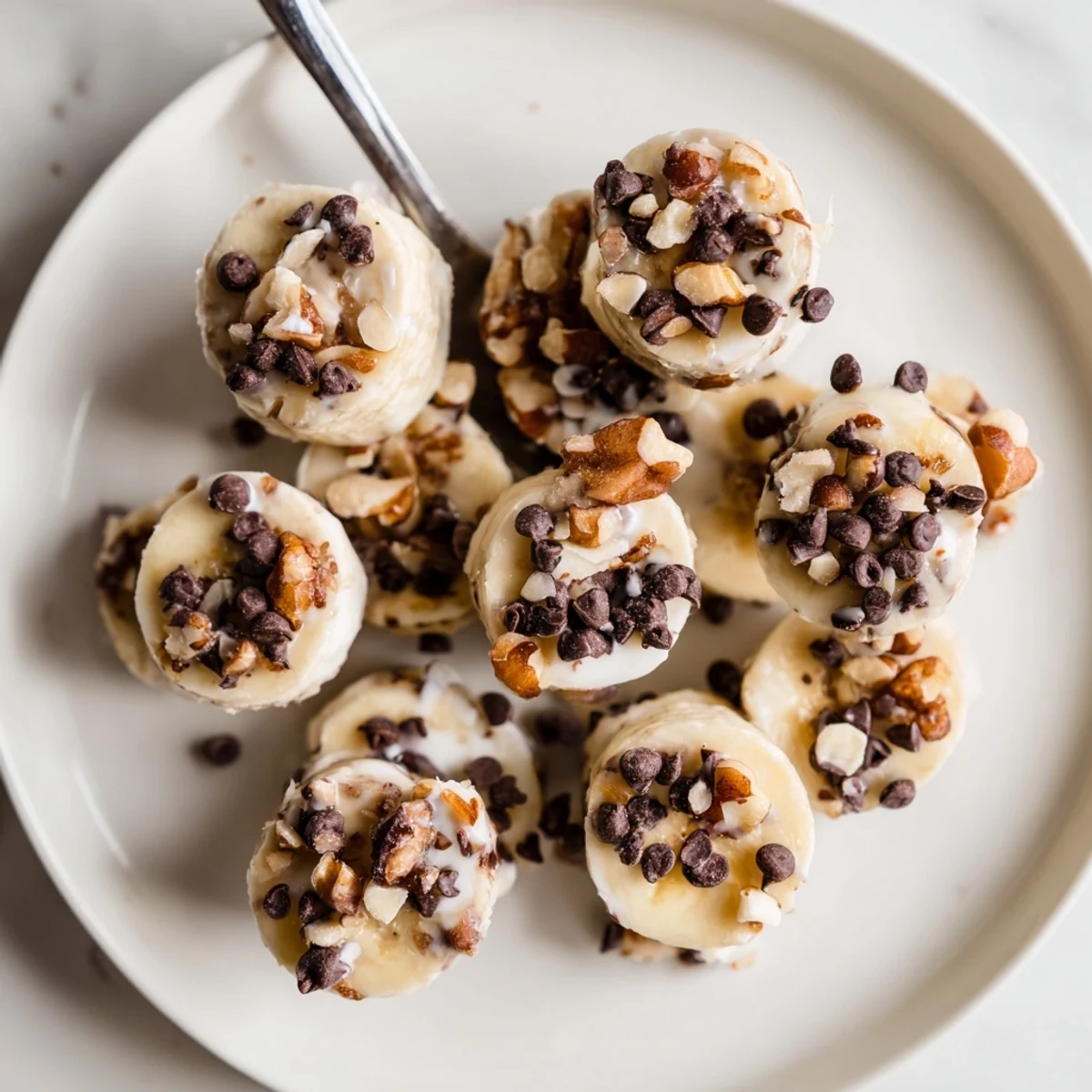 Homemade Frozen Banana Yogurt Bites, smooth yogurt coating and crunchy nut topping