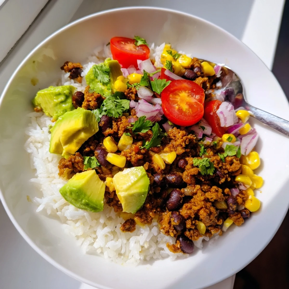 Colorful black bean and rice bowl garnished with diced tomatoes and lime wedges