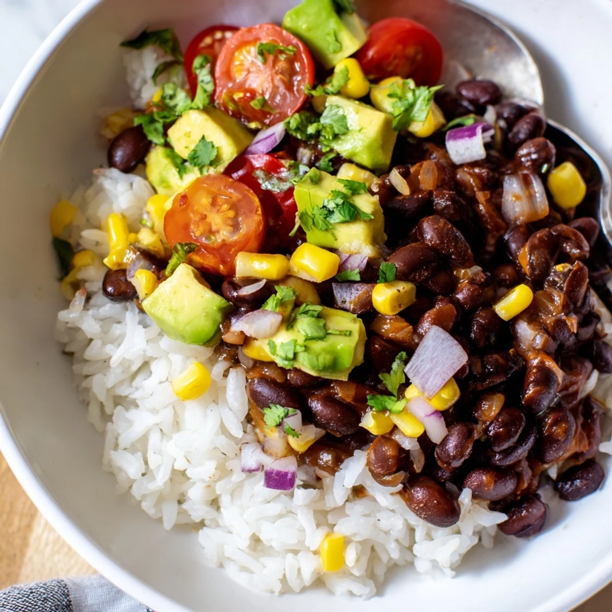Hearty black bean and rice bowl served with sweet corn and shredded cheese