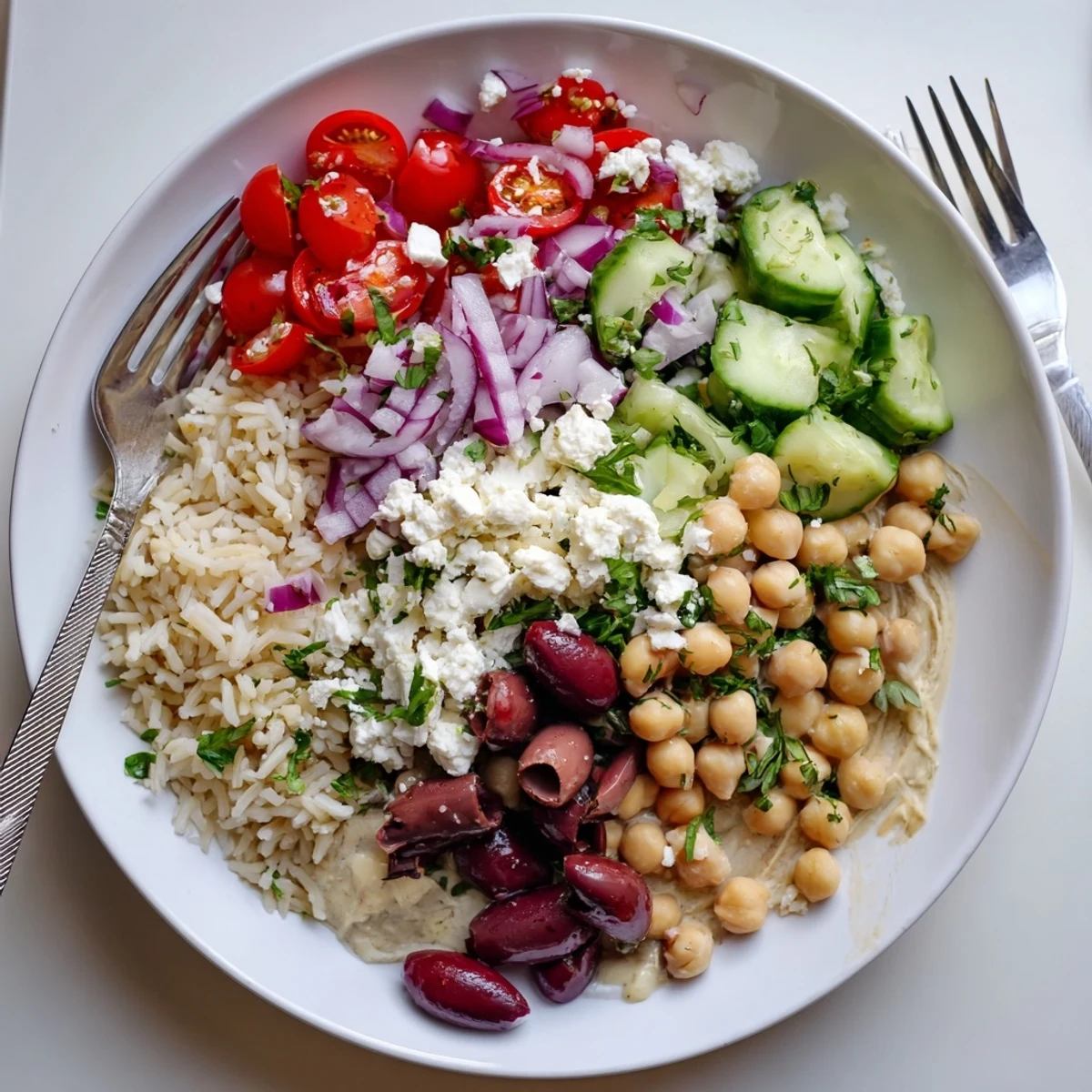 Colorful Mediterranean rice bowl topped with crisp vegetables, chickpeas, and crumbled feta cheese
