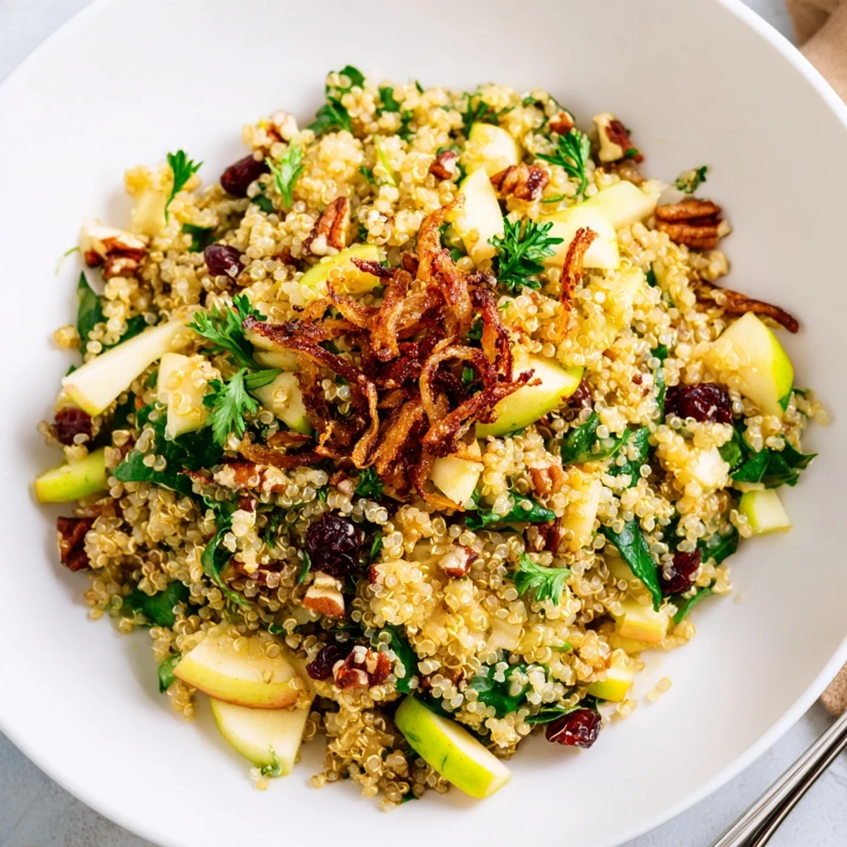 Honey Mustard Quinoa Apple Salad topped with golden crispy shallots on a rustic white plate