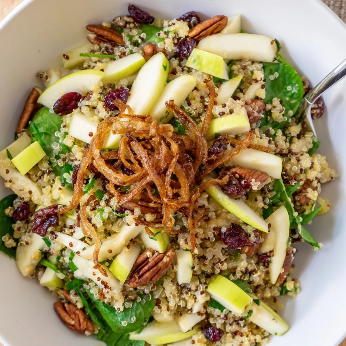 A close-up of honey mustard quinoa apple salad with cranberries, pecans, and fresh greens