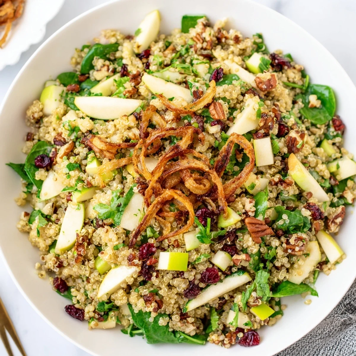 Tangy honey mustard quinoa apple salad served in a bowl with crisp apple chunks and herbs